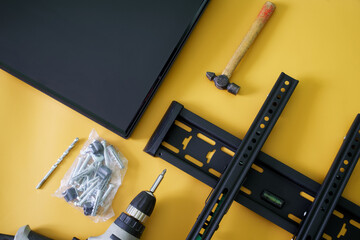 TV wall bracket laid out with screws, wall plugs, drill and hammer